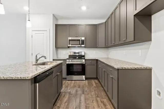 a kitchen with granite countertop a stove top oven a sink dishwasher and a refrigerator with wooden floor