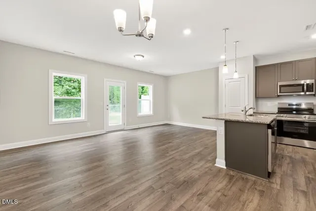 a kitchen with granite countertop a stove a sink a refrigerator and a wooden floor