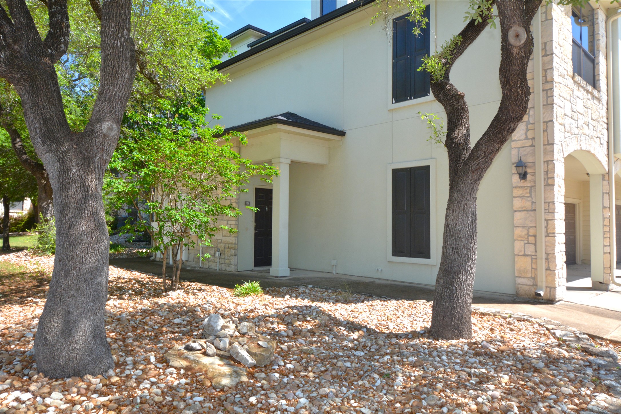 7701 Rialto Boulevard, Unit 124 Austin, TX 78735 - Photo 2 of 22 The property exterior features a light-toned stucco and stone facade, accented by dark window shutters