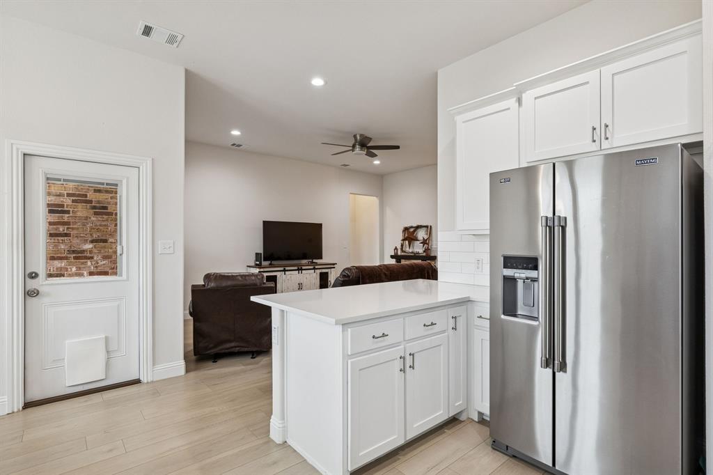 388 Montague Street Pilot Point, TX 76258 - Photo 13 of 28 a kitchen with white cabinets and stainless steel appliances