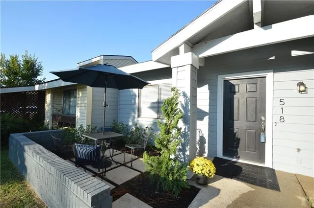 a view of a house with patio furniture and potted plants