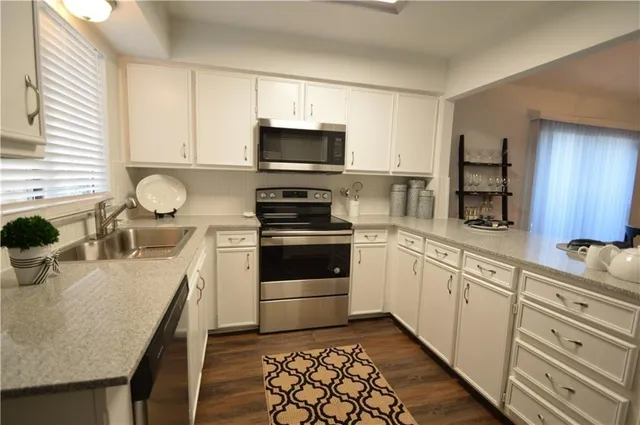 a kitchen with granite countertop a sink appliances cabinets and counter space
