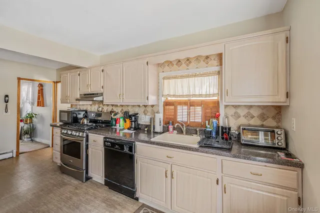 a kitchen with a stove a sink and white cabinets