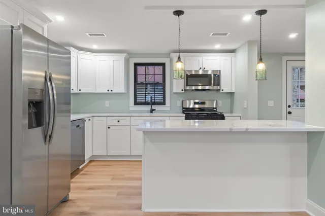 a kitchen with stainless steel appliances granite countertop a refrigerator a sink and a stove