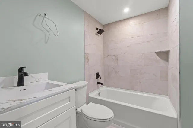 a bathroom with a bathtub shower sink vanity and toilet