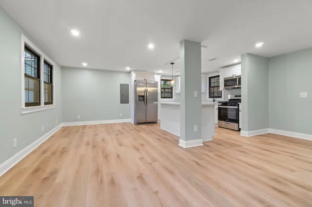 a view of a kitchen with stainless steel appliances kitchen island wooden floor and a refrigerator