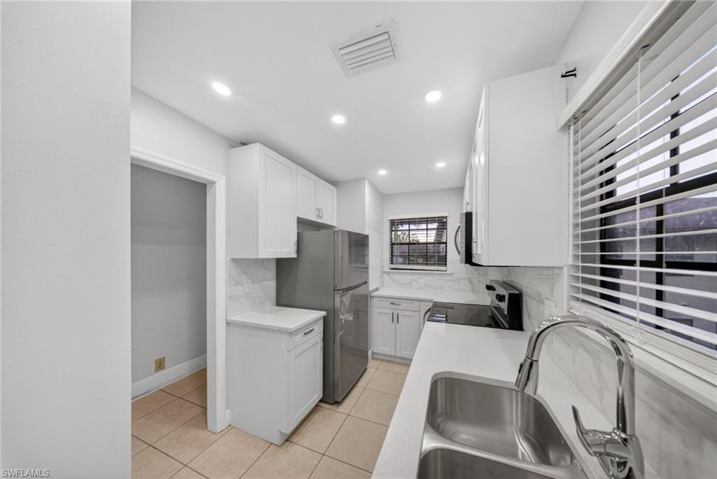 5300 Treetops Drive, Unit I206 Naples, FL 34113 - Photo 3 of 17 a kitchen with a sink and a refrigerator