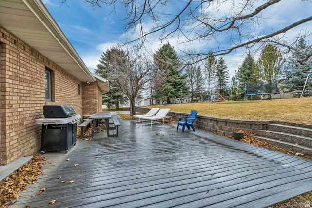 887 Village Way Alpine, UT 84004 - Photo 9 of 28 Wooden deck with a trampoline, a playground, grilling area, and a lawn