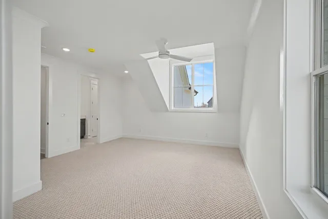 a view of a livingroom with a ceiling fan & windows