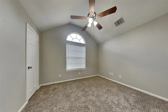 an empty room with a chandelier fan and windows