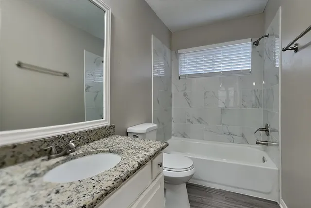 a bathroom with a granite countertop sink toilet and shower