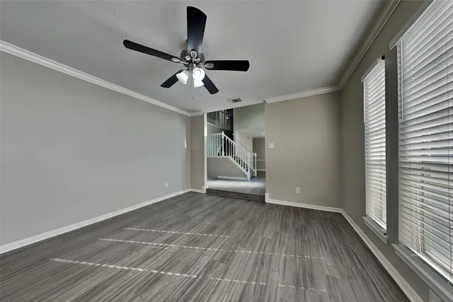 a view of empty room with wooden floor and fan