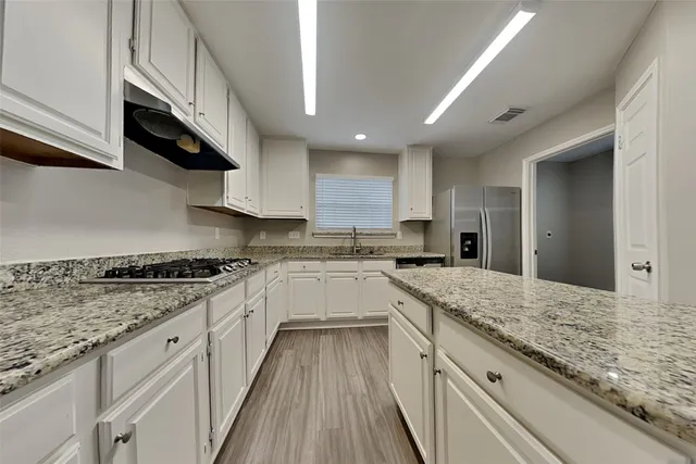 a kitchen with granite countertop kitchen island wooden cabinets and stainless steel appliances
