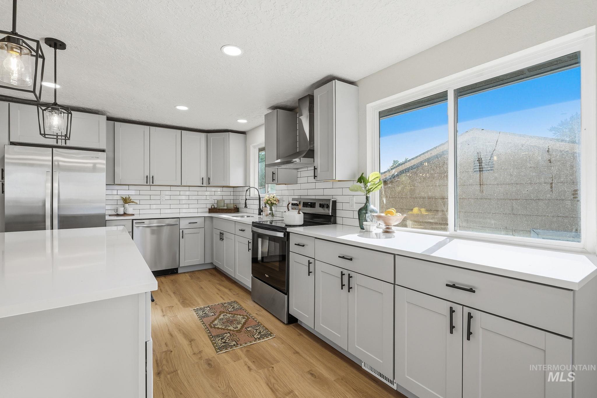 1990 Panama Street Boise, ID 83705 - Photo 22 of 50 Modern kitchen featuring light gray cabinetry with black hardware, white countertops, stainless steel appliances, a white subway tile backsplash, and wood-finish flooring