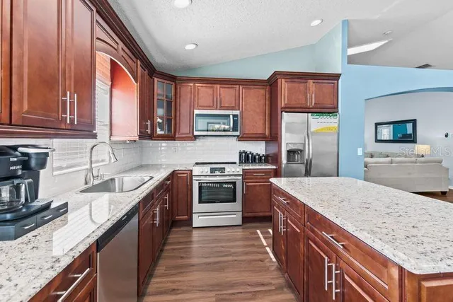 a kitchen with stainless steel appliances granite countertop a stove a sink and a microwave
