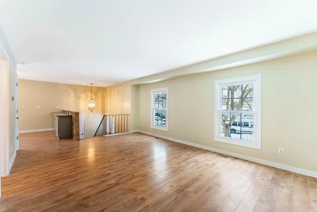 a view of an empty room with window and wooden floor