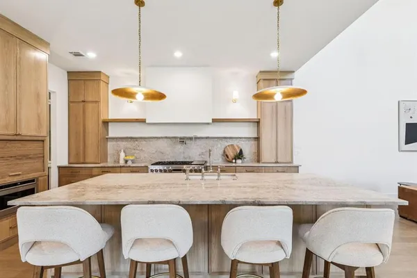 a kitchen with stainless steel appliances granite countertop a table chairs sink and white cabinets
