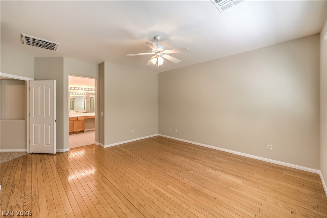 3713 Spring Shadow Road Las Vegas, NV 89129 - Photo 22 of 37 A spacious bedroom features warm hardwood flooring and convenient access to an adjoining bathroom.