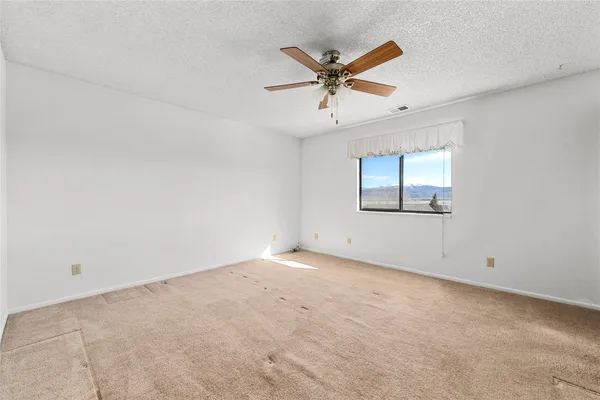 an empty room with a window and a fan