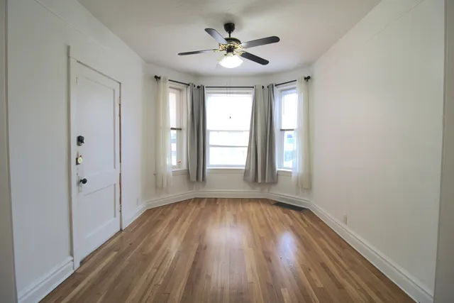 a view of empty room with wooden floor and fan