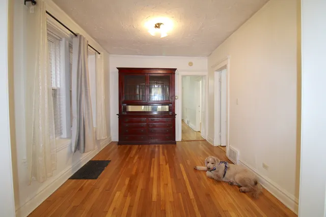 a view of a hallway with wooden floor and a kitchen space