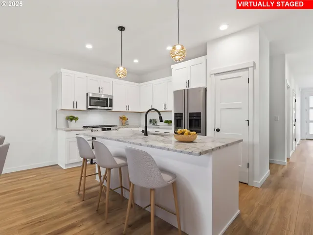 a kitchen with stainless steel appliances kitchen island granite countertop a table chairs and a refrigerator