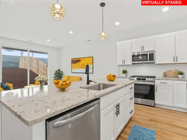 a kitchen with stainless steel appliances granite countertop a sink dishwasher a stove and a refrigerator with wooden floor