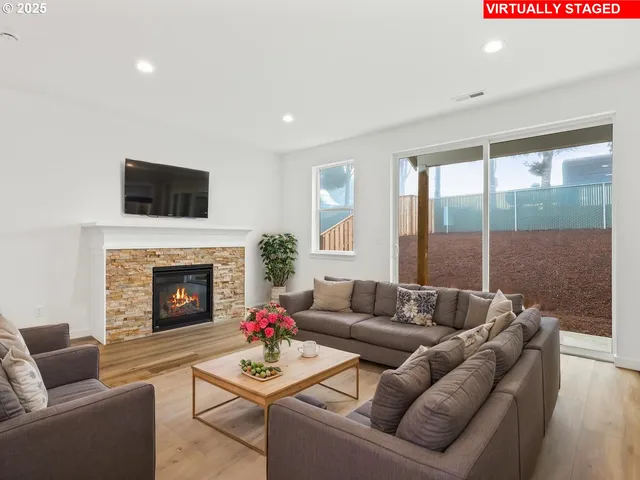 a living room with furniture a fireplace and a floor to ceiling window