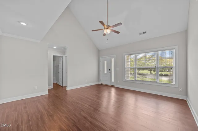 a view of an empty room with a window and wooden floor