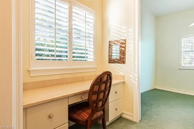 a view of a workspace with furniture and a window