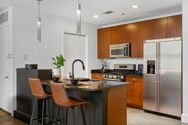 a kitchen with stainless steel appliances granite countertop a stove a refrigerator a kitchen island a dining table and chairs