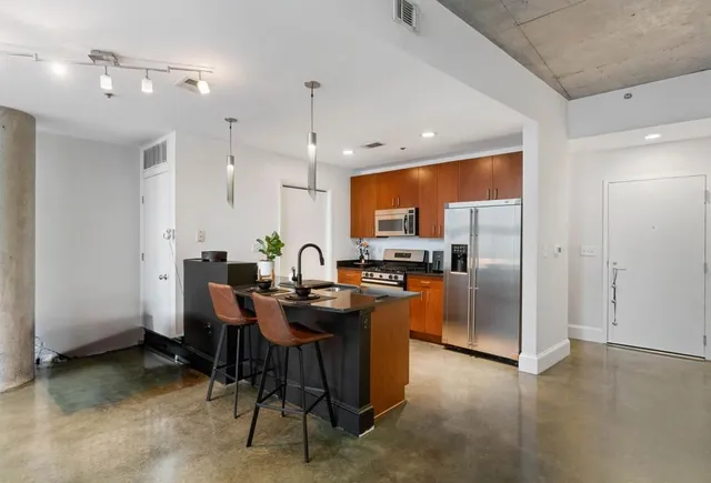 a kitchen with stainless steel appliances kitchen island granite countertop a refrigerator a sink a stove a dining table and chairs