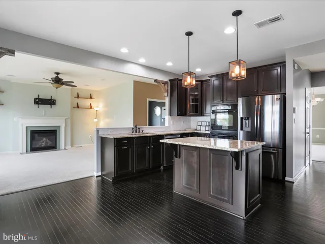 a large kitchen with a stove a sink dishwasher a refrigerator and a fireplace with wooden floor