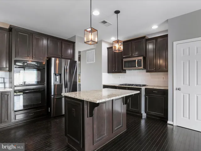 a kitchen with stainless steel appliances kitchen island granite countertop a stove refrigerator and microwave