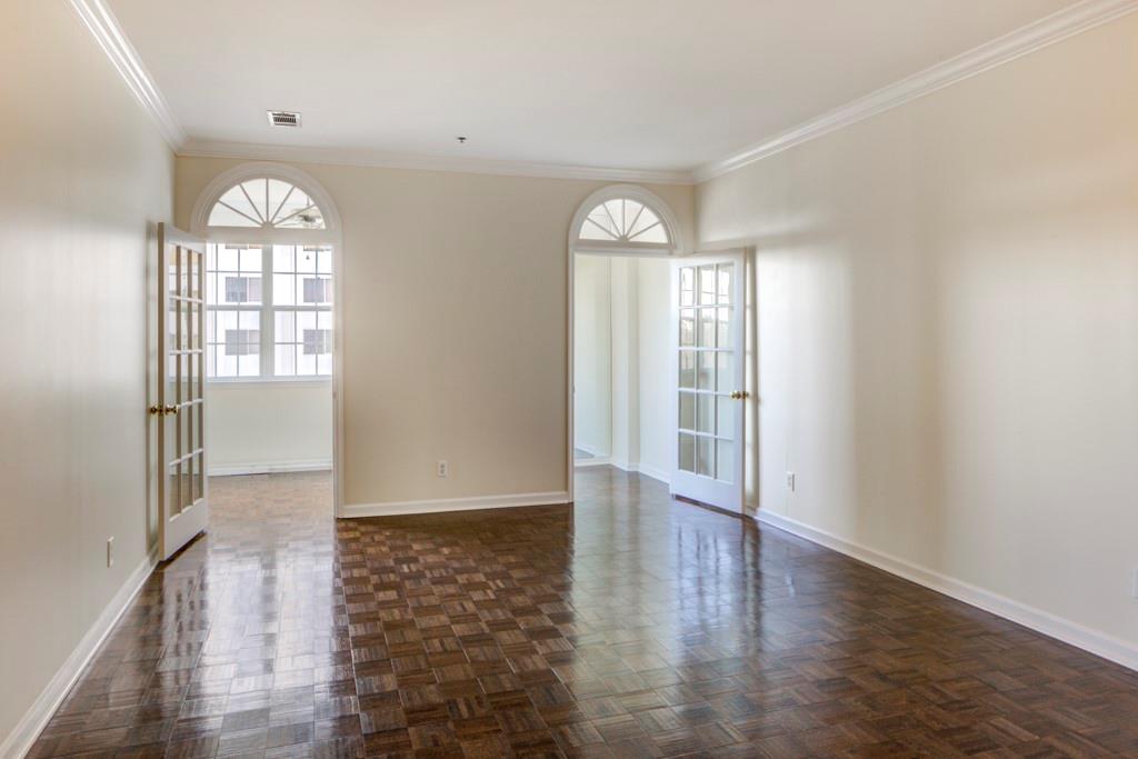 an empty room with wooden floor mirror and windows