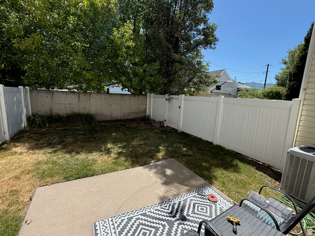183 East 820 South Centerville, UT 84014 - Photo 12 of 14 Private backyard space featuring a concrete patio, a section of lawn, and a white privacy fence with a gate