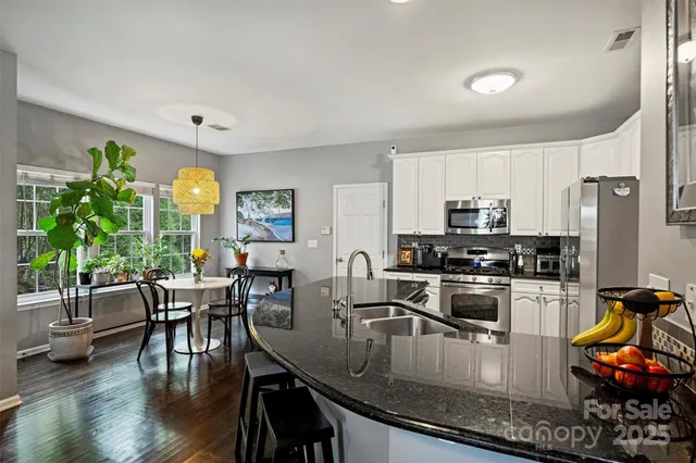 a kitchen with granite countertop a table chairs stove and refrigerator