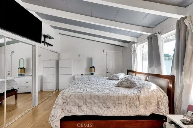 a bedroom with a large bed a flat tv screen and a dresser