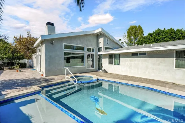 a view of a backyard with swimming pool and sitting area