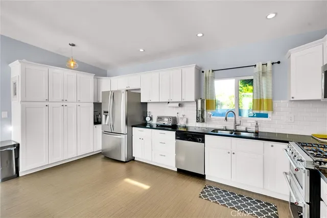 a kitchen that has a lot of white cabinets and stainless steel appliances