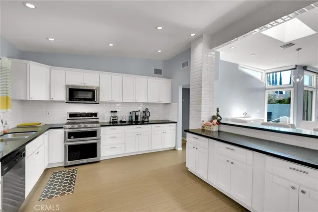 a kitchen with granite countertop white cabinets and stainless steel appliances