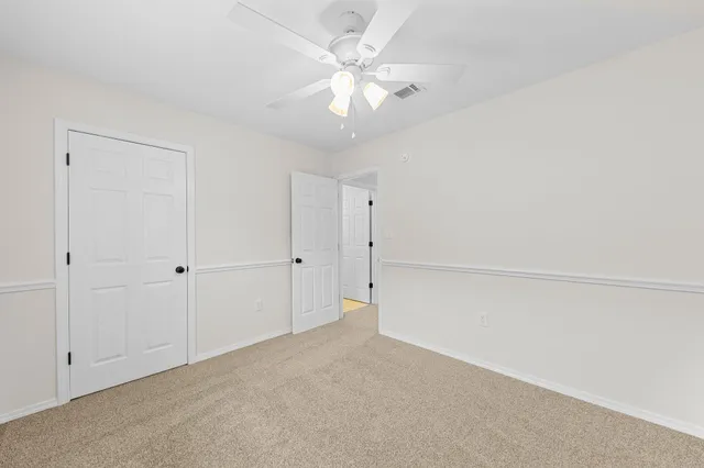 an empty room with windows and fan