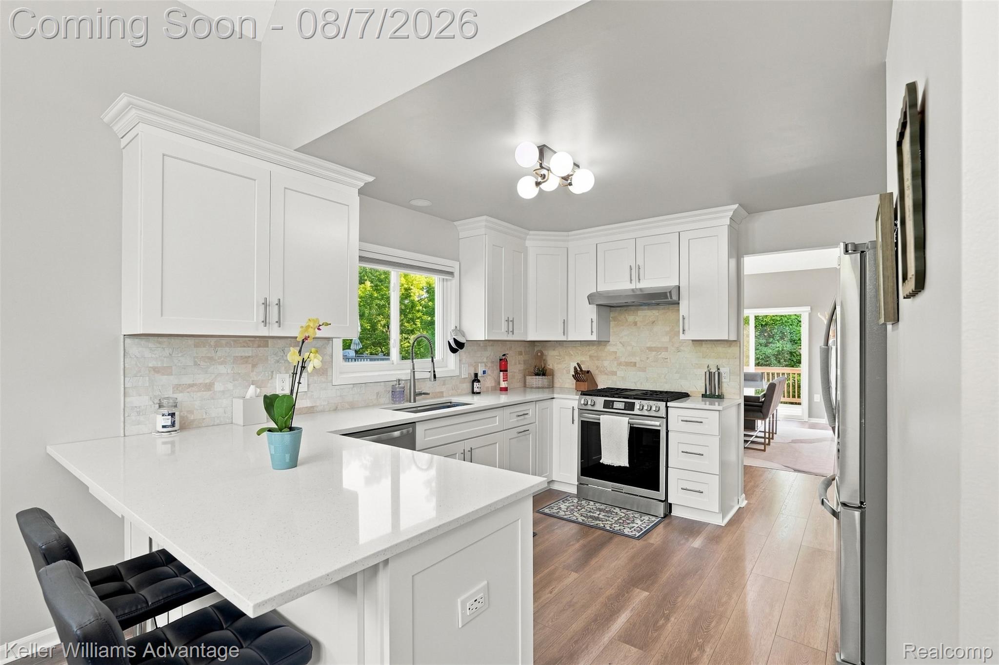5325 Simpson Lake Road West Bloomfield, MI 48323 - Photo 11 of 43 Kitchen featuring white shaker cabinetry, light countertops, wood-finish flooring, stainless steel appliances, and a tiled backsplash