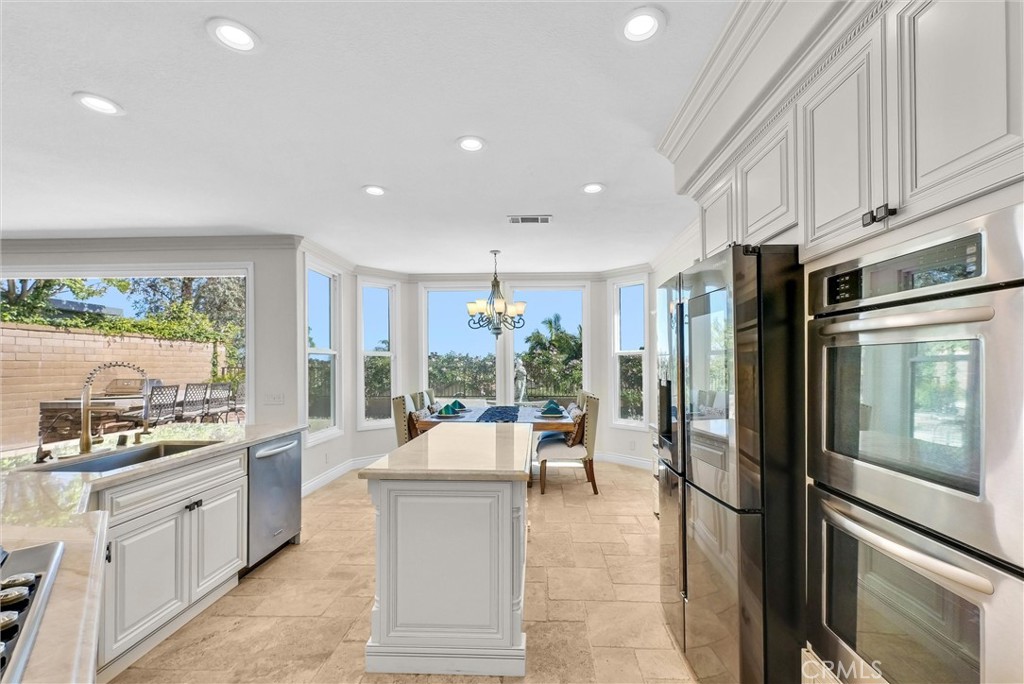 25672 Raintree Road Laguna Hills, CA 92653 - Photo 18 of 50 a room with stainless steel appliances kitchen island granite countertop a refrigerator a sink a stove and white cabinets with wooden floor