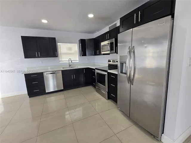 a large kitchen with stainless steel appliances granite countertop a refrigerator and a sink