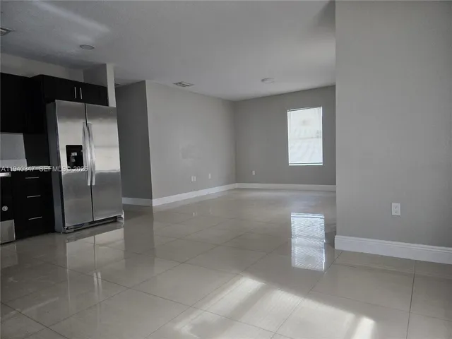 a view of a refrigerator in kitchen and empty room