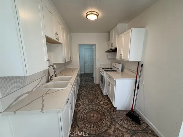 a kitchen with granite countertop a sink stove and refrigerator