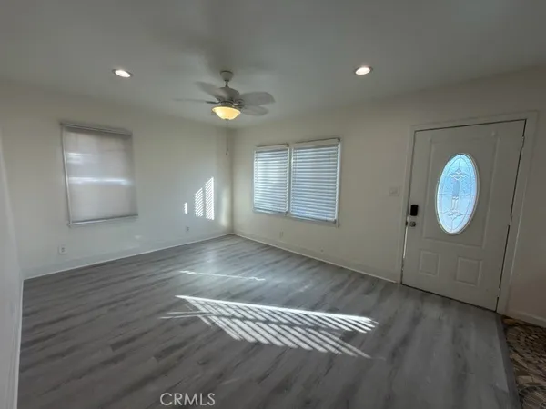 a view of empty room with wooden floor and fan