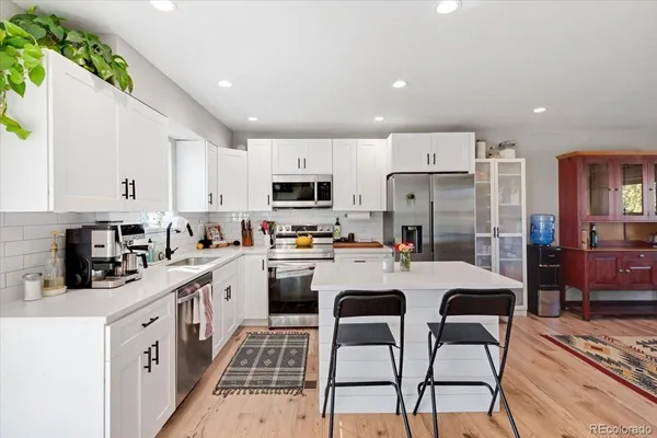 a kitchen with a sink a stove a refrigerator cabinets and a dining table