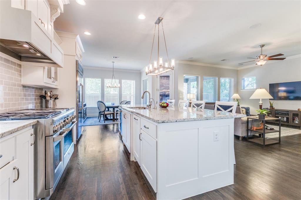 4008 North Cresthaven Road Dallas, TX 75209 - Photo 12 of 37 a large kitchen with stainless steel appliances a stove a sink dishwasher and a dining table with wooden floor